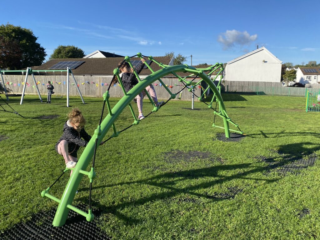 An image of children playing on a climbing frame in a park