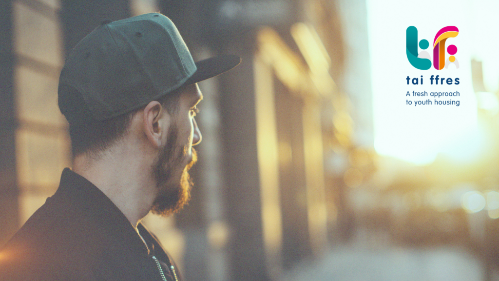 side profile of a young white man wearing a grey cap looking down a street