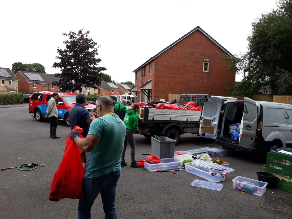 A van full of red rubbish bags, with people loading bags on to the van. A man on the left is holding an open red bag of rubbish.