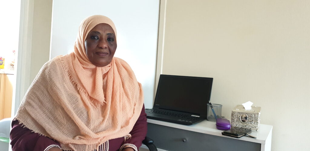 A photo of our Get into Housing placement Hayat, sitting at a desk in front of a computer.