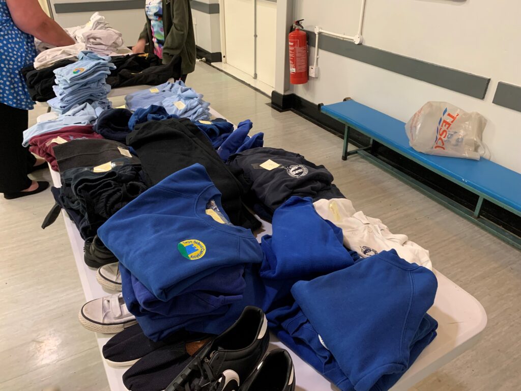 Piles of folded school uniform on a table.