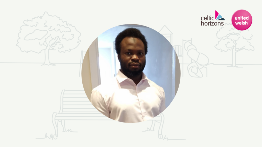 A photo of our Contracts Manager, Sanni. He is wearing a white shirt and is standing in front of a door.