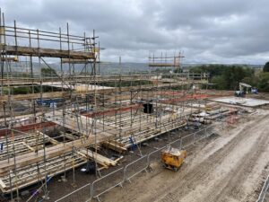 An aerial image of a housing development site with brown mud roads and scaffolding