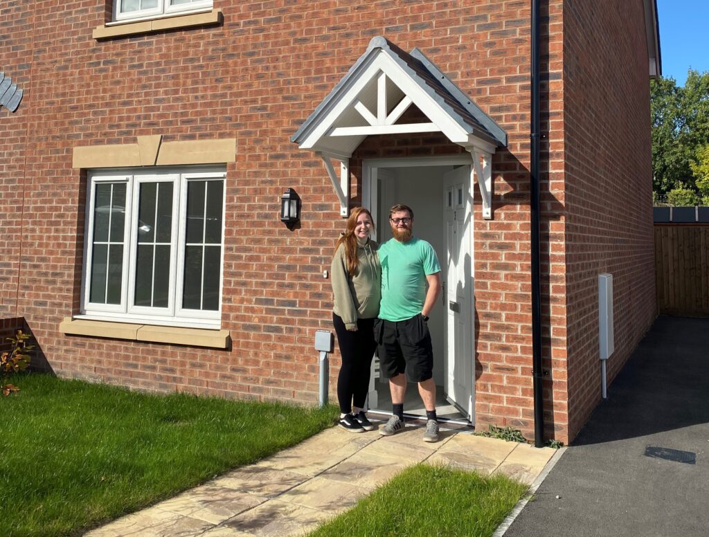 A photo of a couple standing outside their new home in Hengoed, Caerphilly.