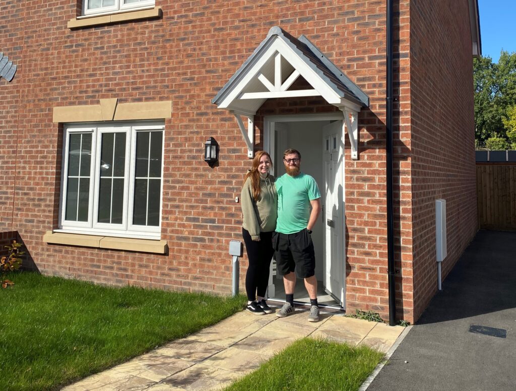 A photo of a couple standing outside their new home in Hengoed, Caerphilly.
