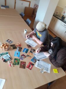 An image of two people looking down sat at a table, doing paper-based work from it