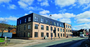 An image of the outside of the Ty Yn Y Pwll apartment building with yellow brick and grey render