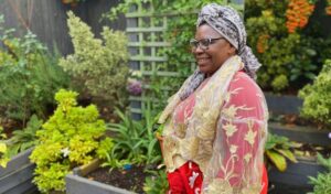 An image of Newtown Court resident Ibere outside in the communal garden in front of leafy, green plants