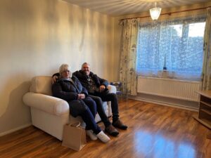 Image of Vadym and Iryna sitting on a sofa in their living room, smiling at the camera.