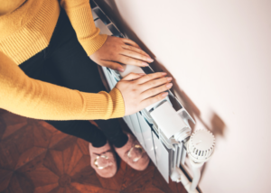 Photo of a woman placing her hands on a radiator.