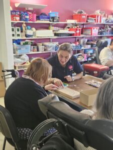 Photo of our volunteer Michelle at the Memory and Craft Club, helping a resident paint a memory box
