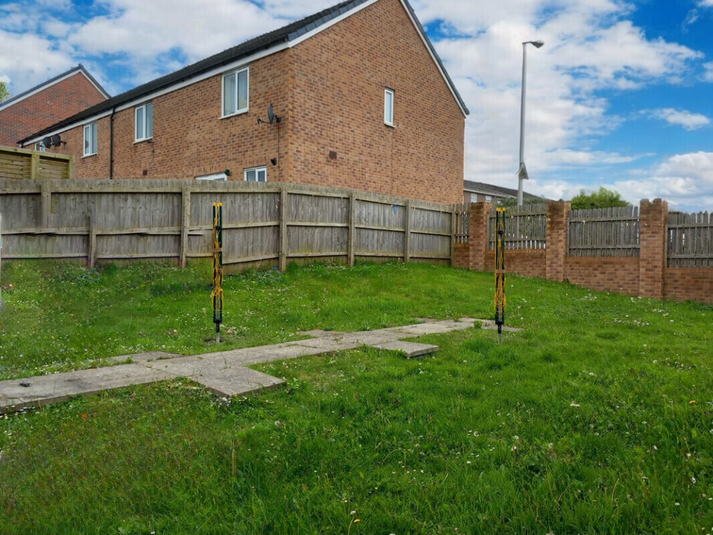 A photo of the communal garden space in Treharne Road, Barry. It is a large grass area with two rotary washing lines.