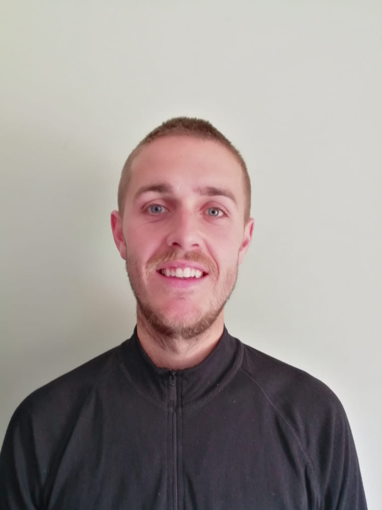 An image of a man with short light hair wearing a black jumper.