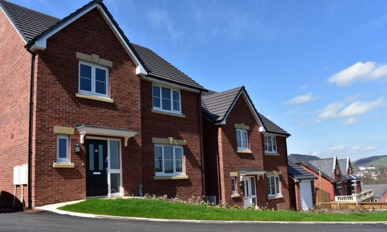 An image of two new builds with dark brick, with blue sky in the background.