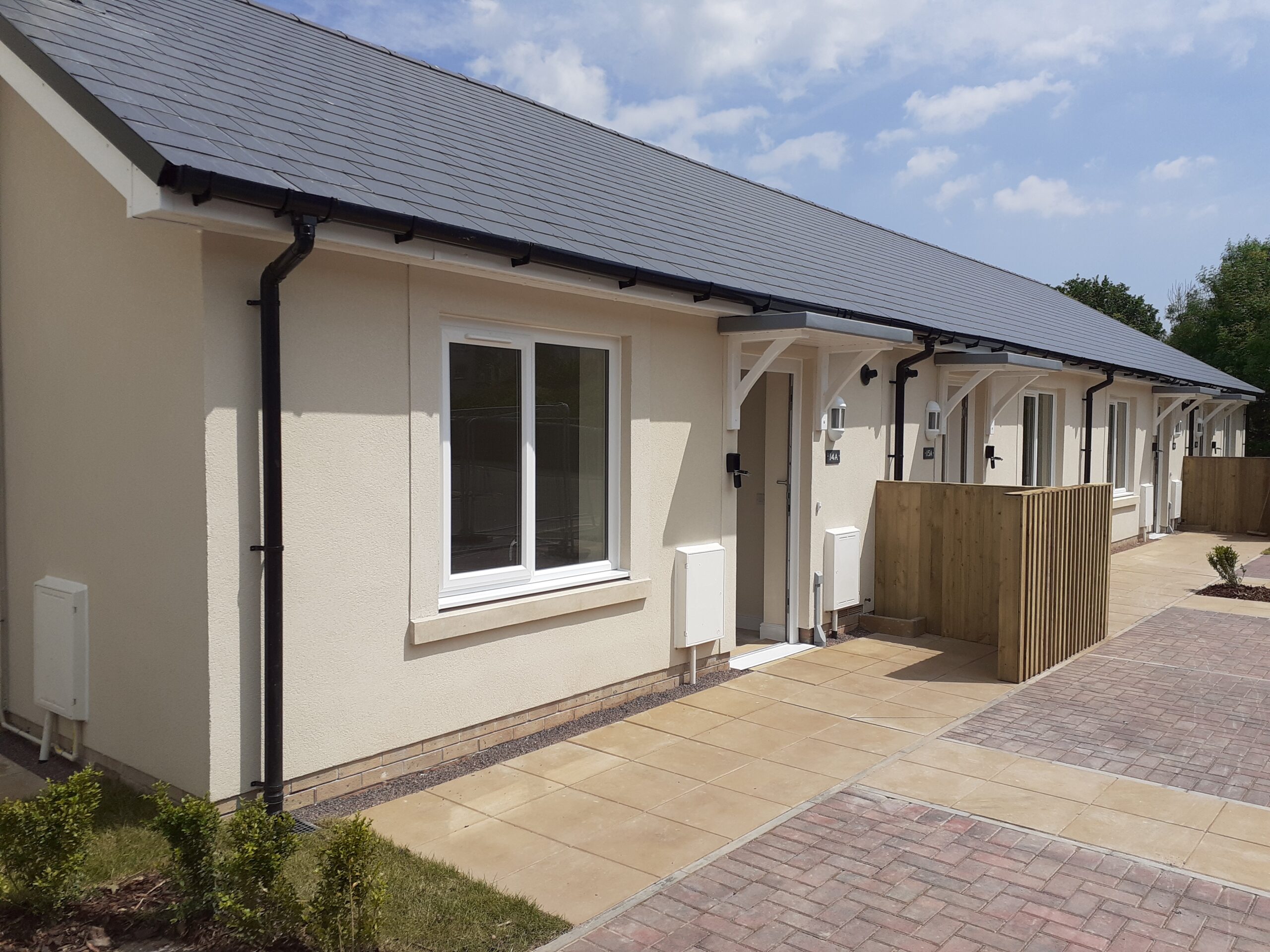 External photo of light cream bungalows with black rooves