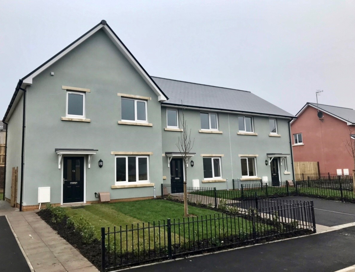 An external photo of three light blue homes with black rooves.