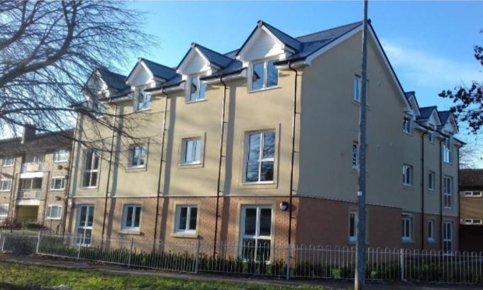 A photo of the outside of a block of flats in the sunshine.