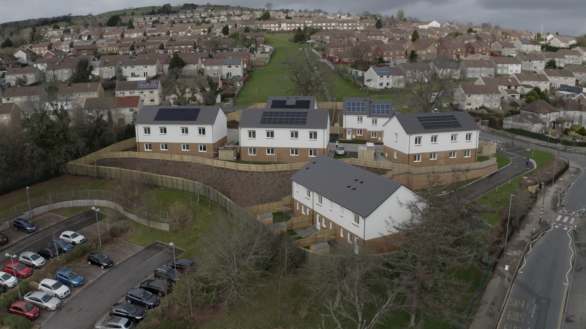 Aerial view of 19 new homes with grey rooves, solar panels and white walls