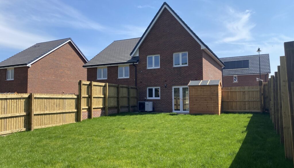 The back of a home in Penallta, Caerphilly. There is a large patch of green grass in front of the rear of the home.