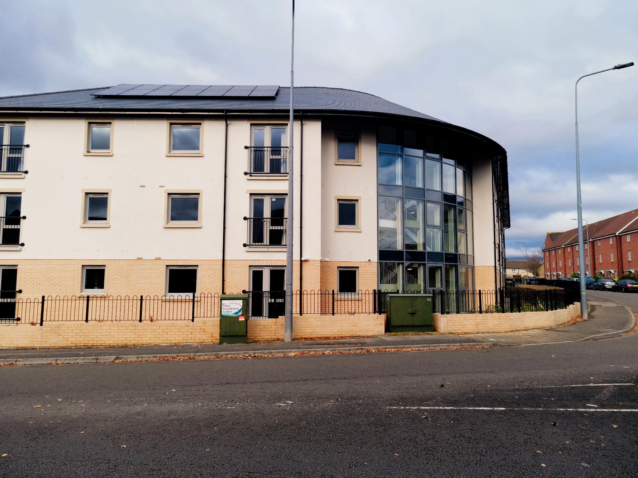 An external image of United Welsh's new development in St Mellons. The outside of the building is a cream colour, with a curved front entrance area.